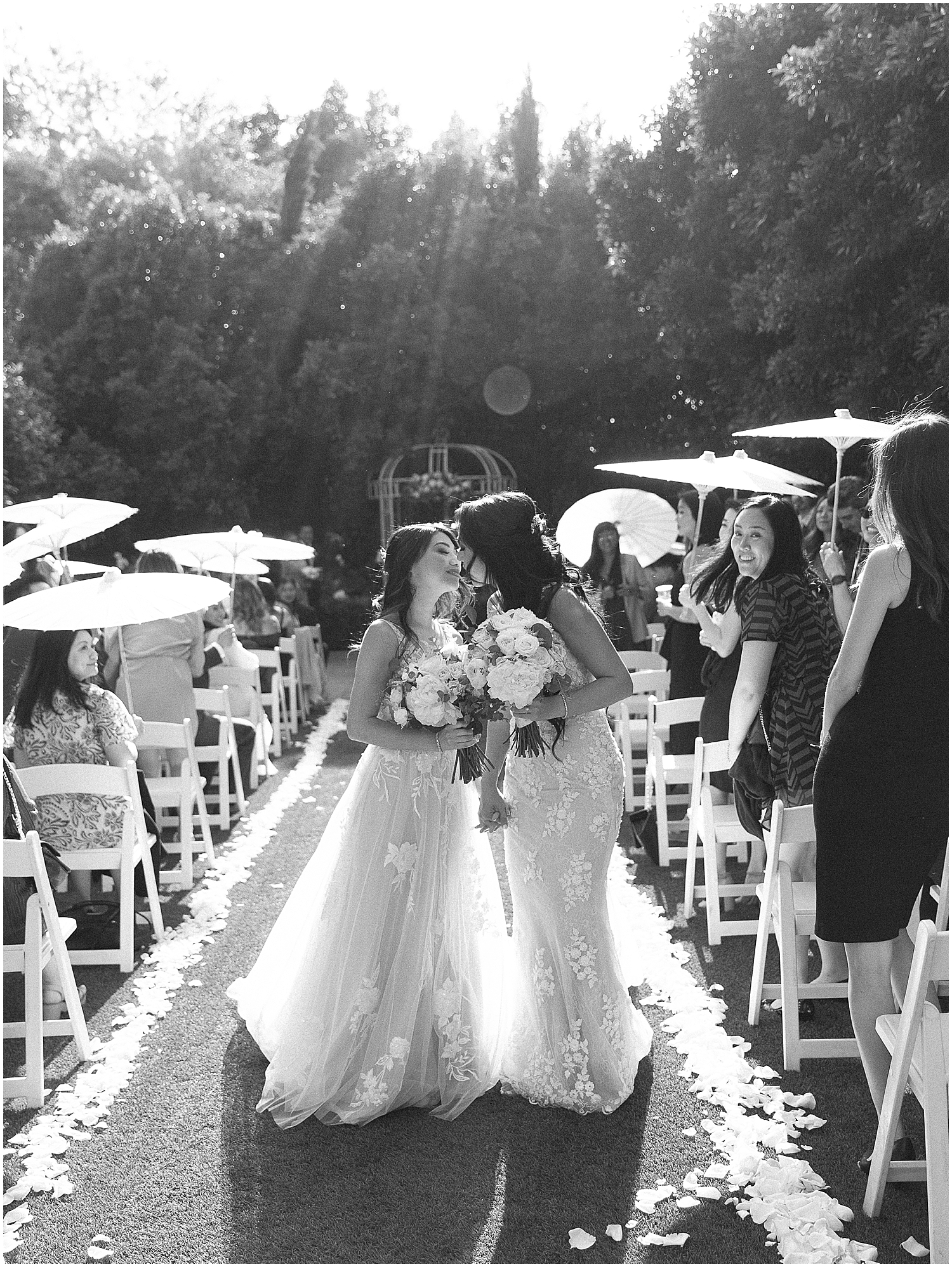 Brides exchanging vows in a lush garden setting at Christmas House Inn.
