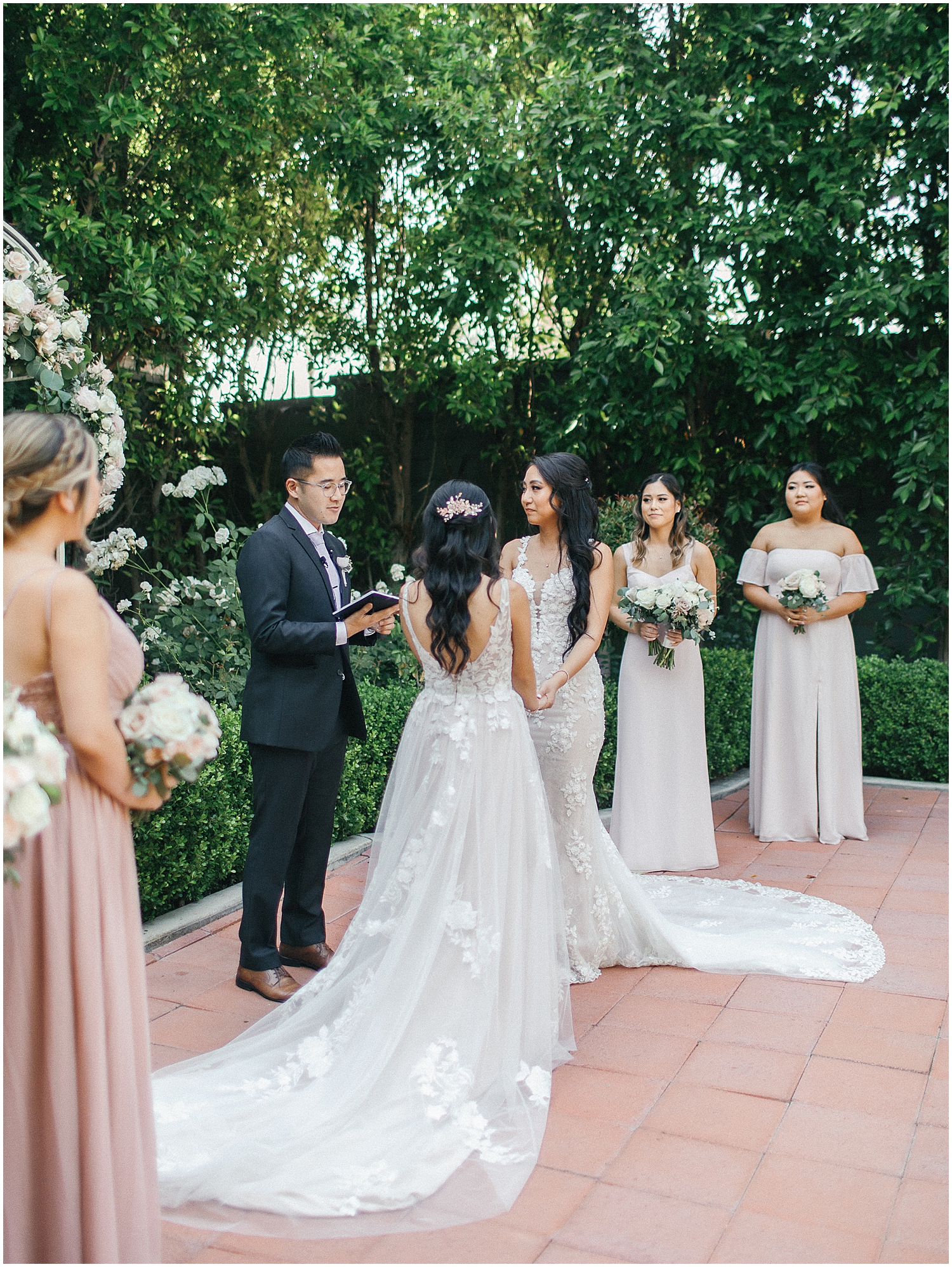 Brides exchanging vows in a lush garden setting at Christmas House Inn.