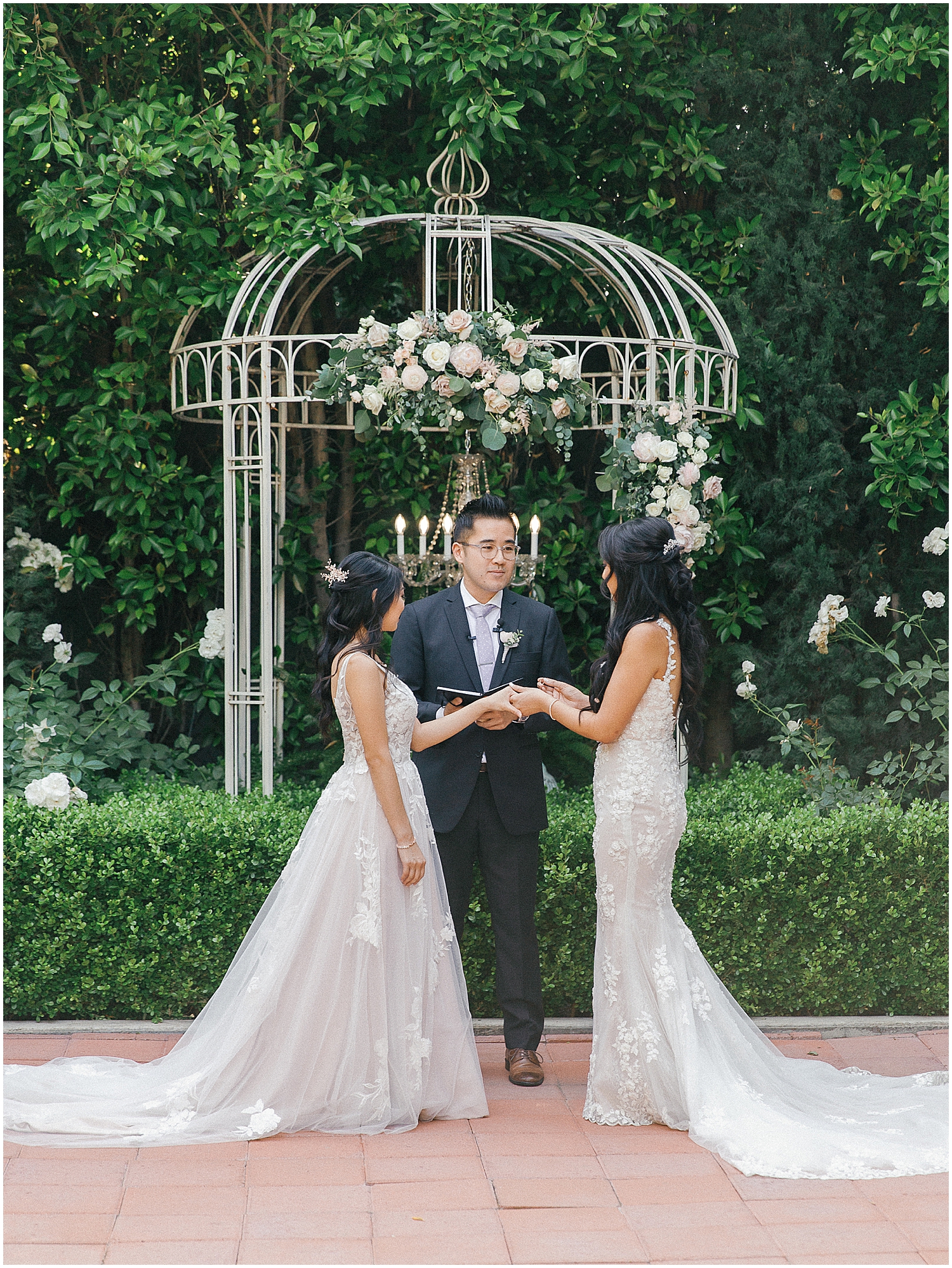 Brides exchanging vows in a lush garden setting at Christmas House Inn.