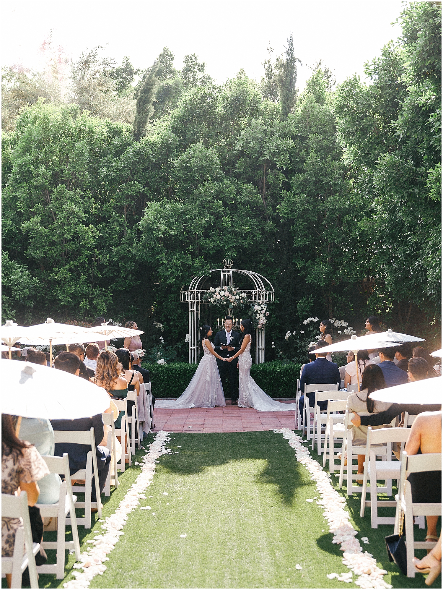 Brides exchanging vows in a lush garden setting at Christmas House Inn.