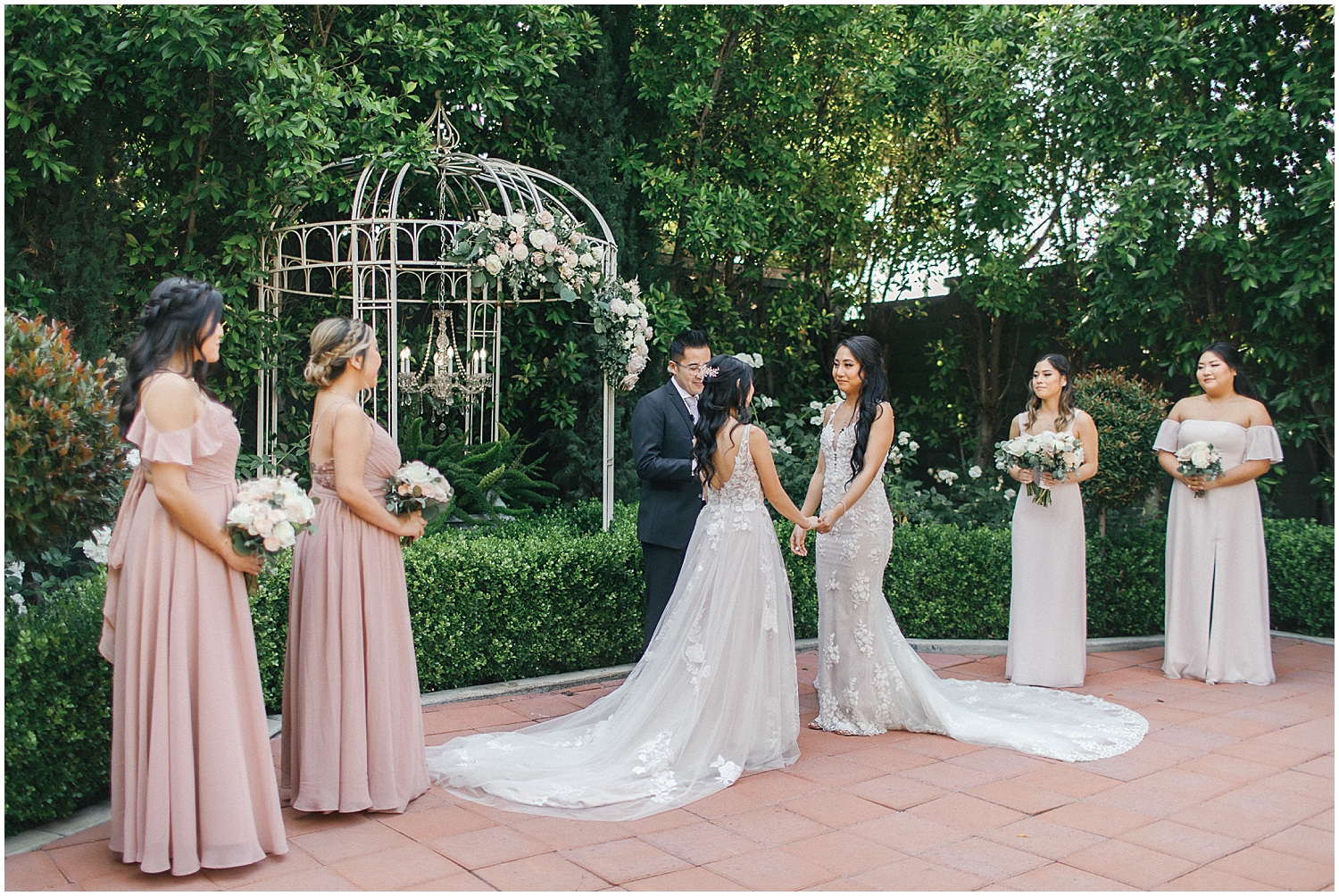 Brides exchanging vows in a lush garden setting at Christmas House Inn.